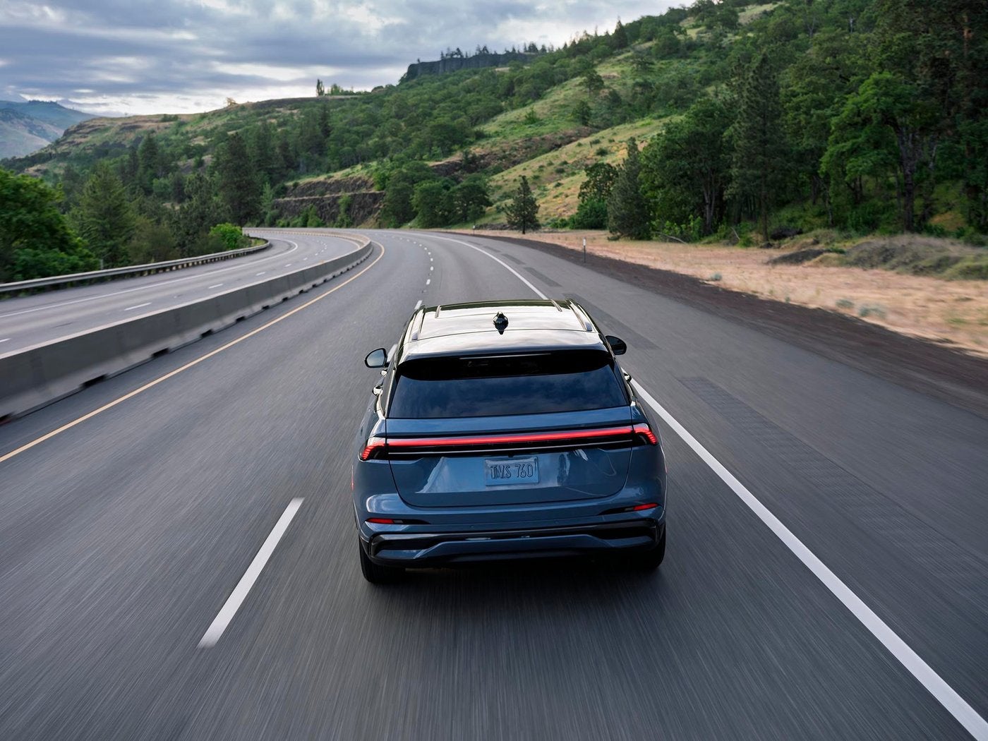 Lincoln Nautilus driving on a highway with its full width taillights on