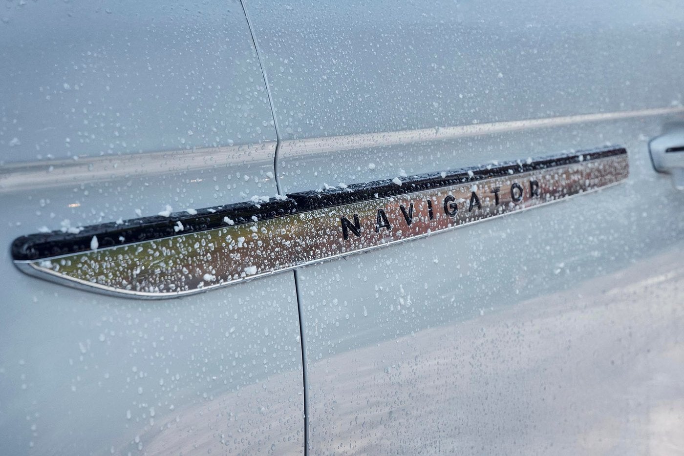 Close view of the Navigator door badge on a Lincoln covered in raindrops