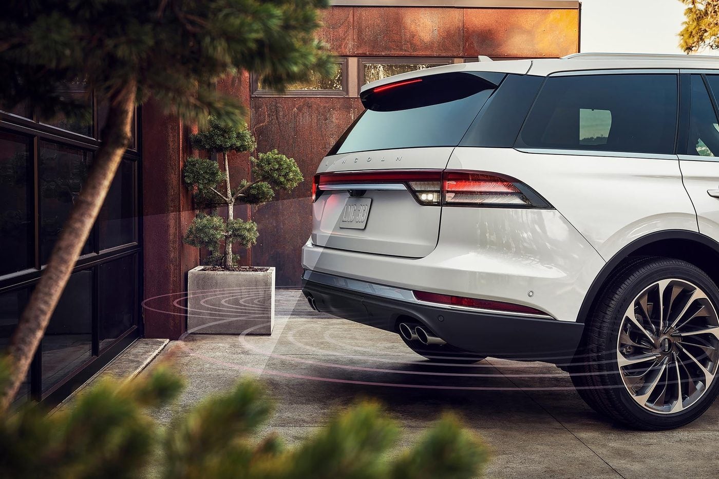 White Lincoln Aviator backing toward a garage with parking sensor beams shown