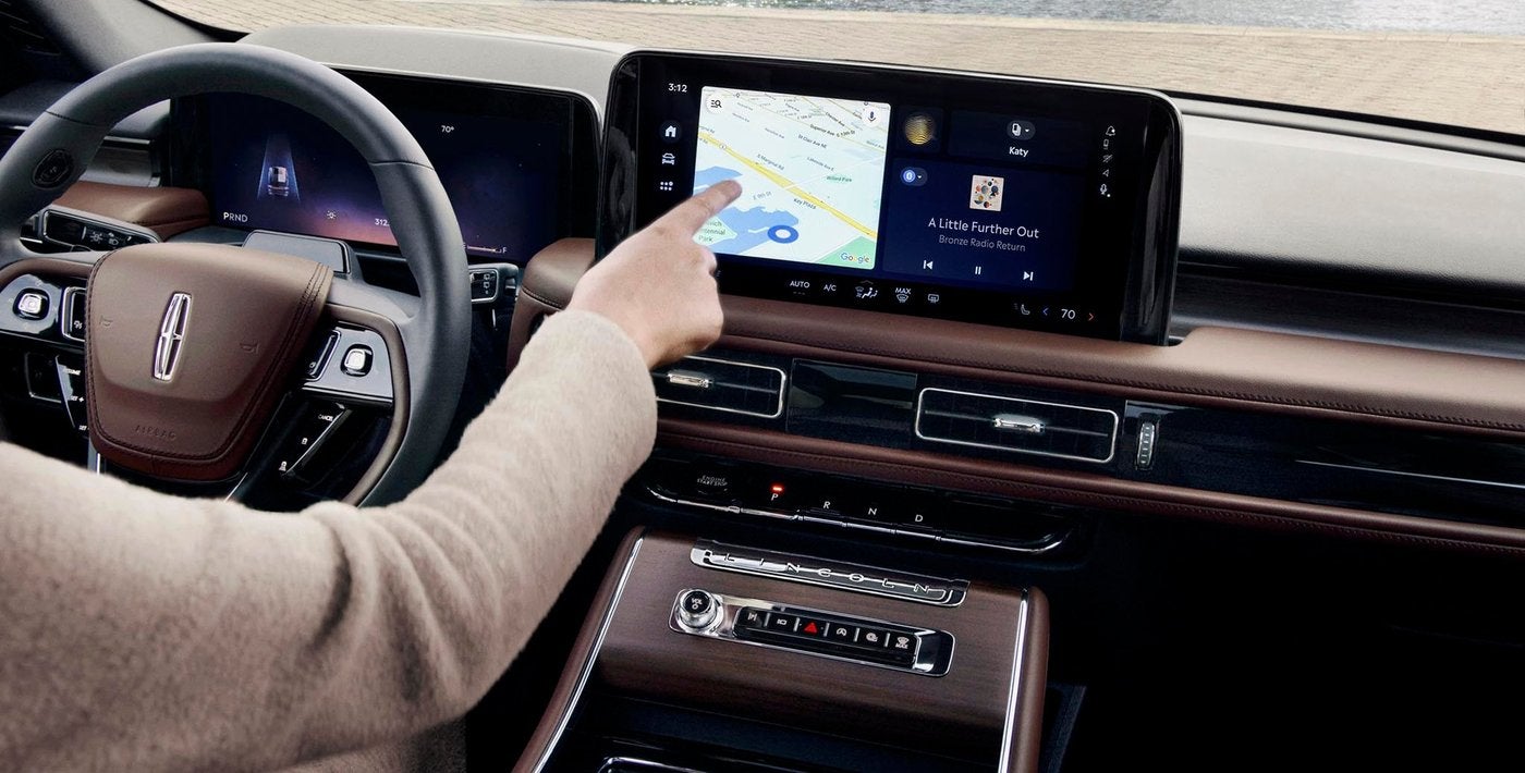 Hand reaching to the center touchscreen map in a Lincoln Aviator