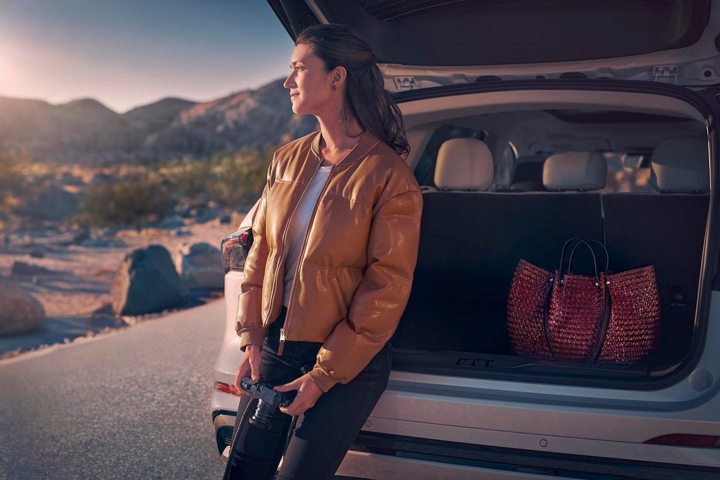 Woman standing at the open cargo area of a Lincoln Nautilus at sunset