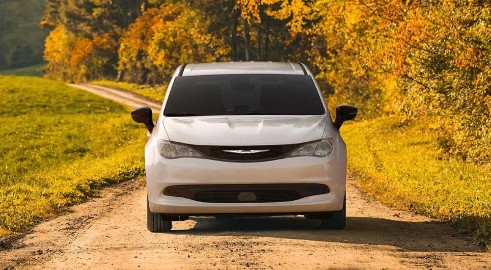 Head-on view of a white 2025 Chrysler Voyager driving on a sunny day.