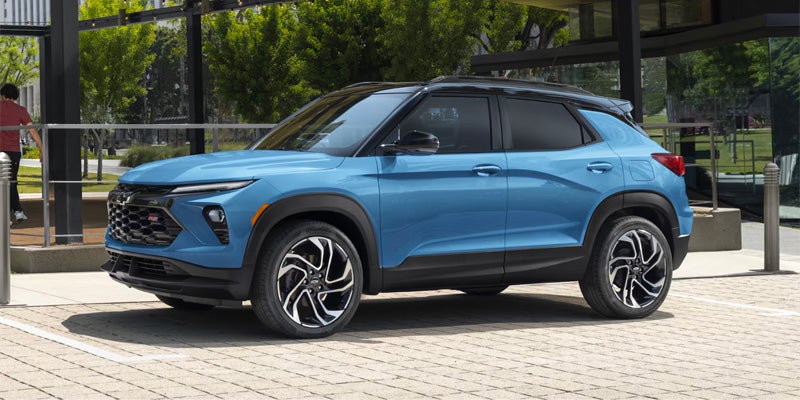 Light blue Chevrolet Trailblazer parked on a paved lot with trees and buildings in the background.