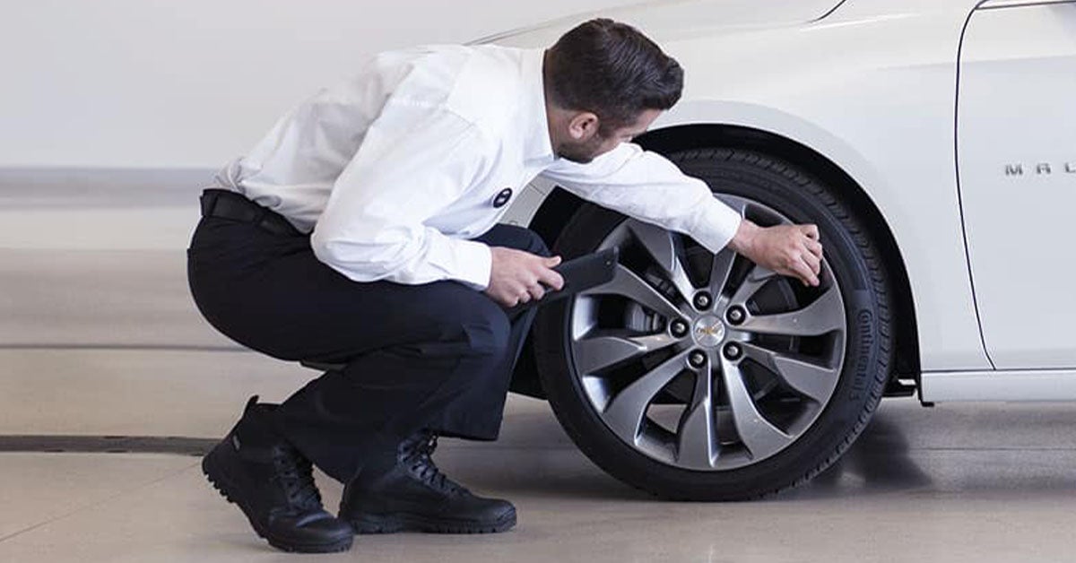 Service technician looking at Chevy wheel