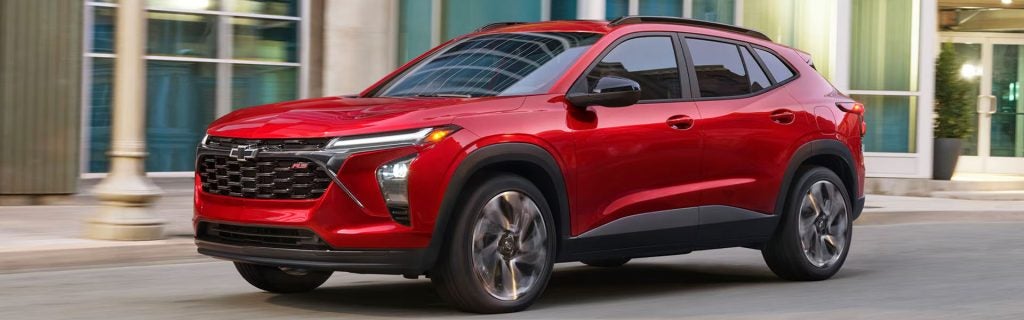 Red Chevrolet SUV driving down a city street.