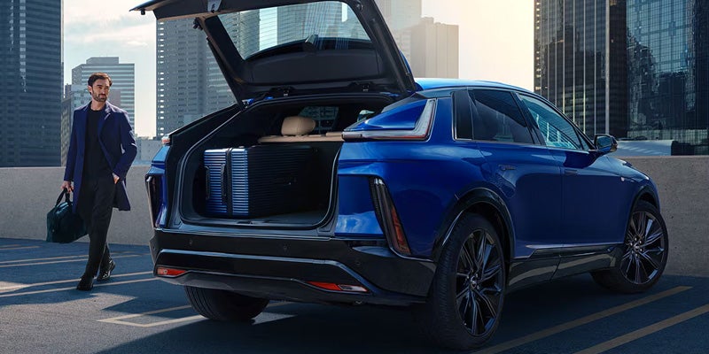 Blue Cadillac LYRIQ SUV with open trunk and a man walking nearby.