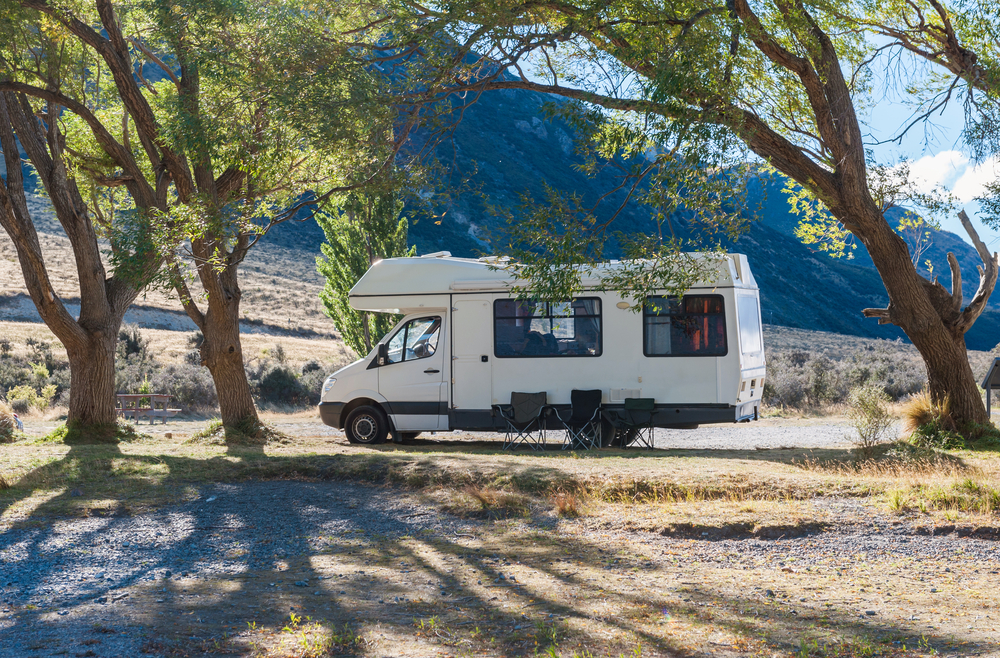 RV right angle view parked under the trees