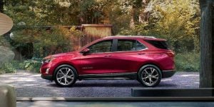 Profile view of a 2021 Chevrolet Equinox parked in a driveway in front of a wooden fence. | Chevrolet dealer in Macedon, NY