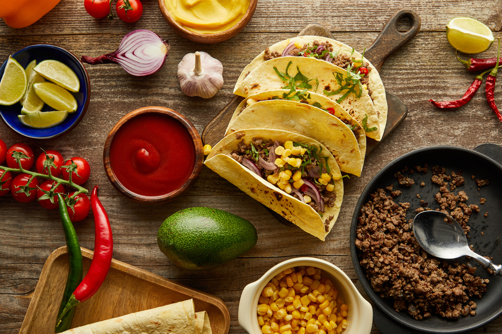 2 tacos surrounded by ingredients and a lime
