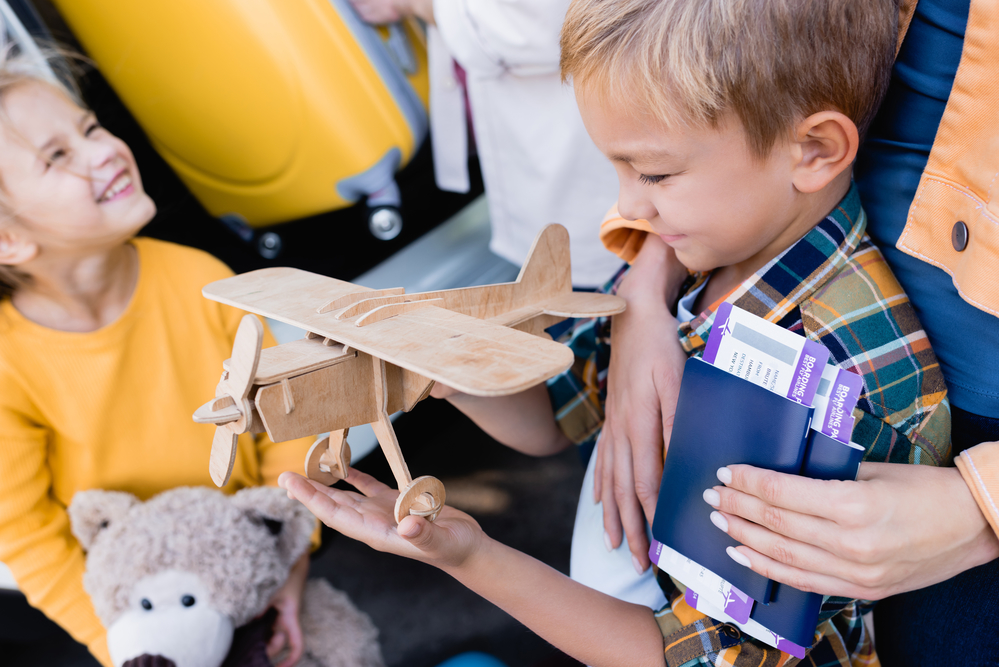 Little boy with wood plane toy and other little boy with a dog stuffed animal