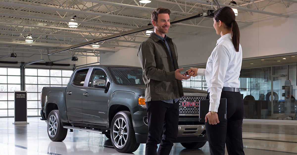 GMC service staff returning truck keys to a customer in a service bay