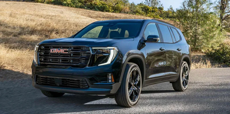 A photo of a 2026 GMC Acadia driving down the road.
