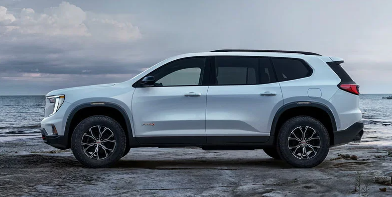 A 2026 GMC Acadia parked on a rocky outcropping overlooking a body of water.
