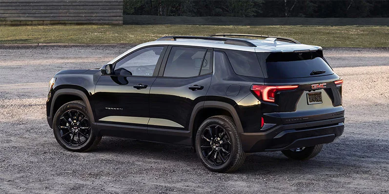 A black 2025 GMC Terrain parked on a gravel driveway.