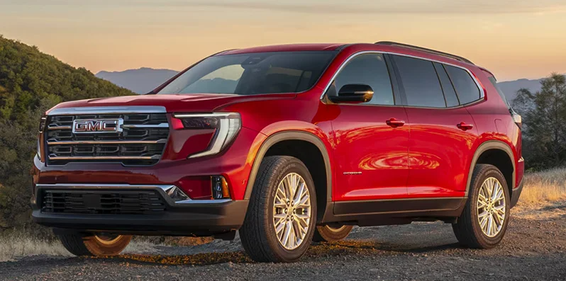A red 2025 GMC Acadia parked on a dirt road.