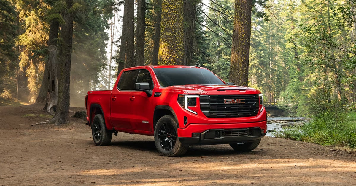 A red GMC Sierra 1500 parked off-road.