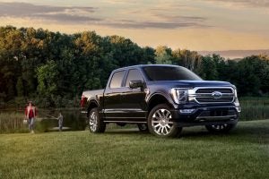 A Ford F-150 parked at a camping ground with a mother and son in the background fishing.