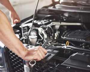 Close-ip of a hand using a wrench on a vehicle.