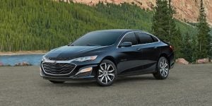 Black Chevrolet Malibu parked in front of a pool.