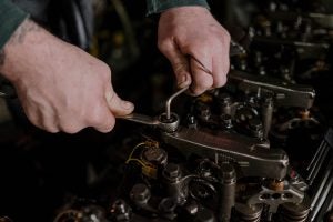 Photo of someone's hands hard at work repairing a vehicle.