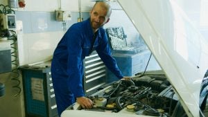 Guy in blue working under the hood of the car.