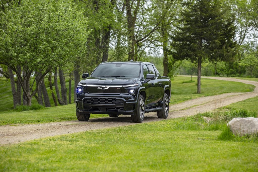 A front 3/4 view of the 2024 Silverado EV RST driving on a dirt trail.