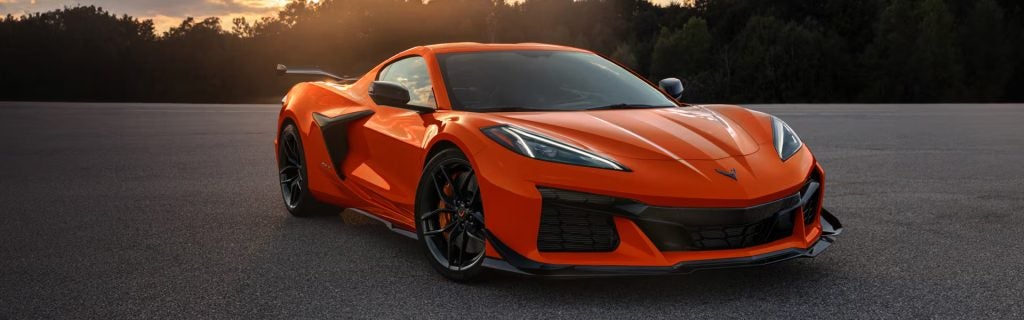 Orange Chevrolet Corvette parked on a track at sunset.