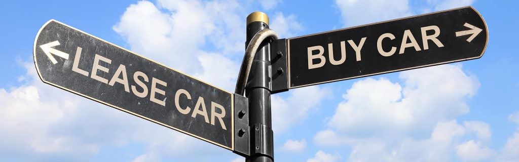Lease or buy car options shown on directional signs against a blue sky.