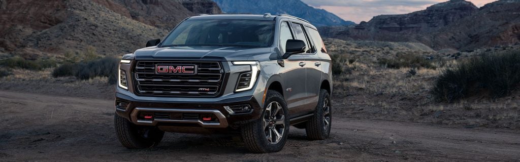 A GMC SUV parked in a rugged, mountainous terrain.