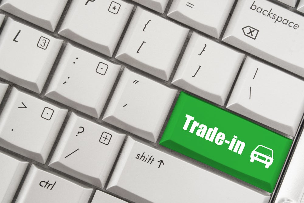 A close-up of a keyboard with a green "Trade-in" key highlighted, featuring a car icon.