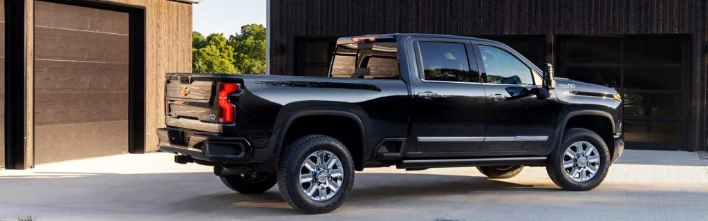 A black Chevrolet Silverado pickup truck parked in front of a modern building with wooden siding.