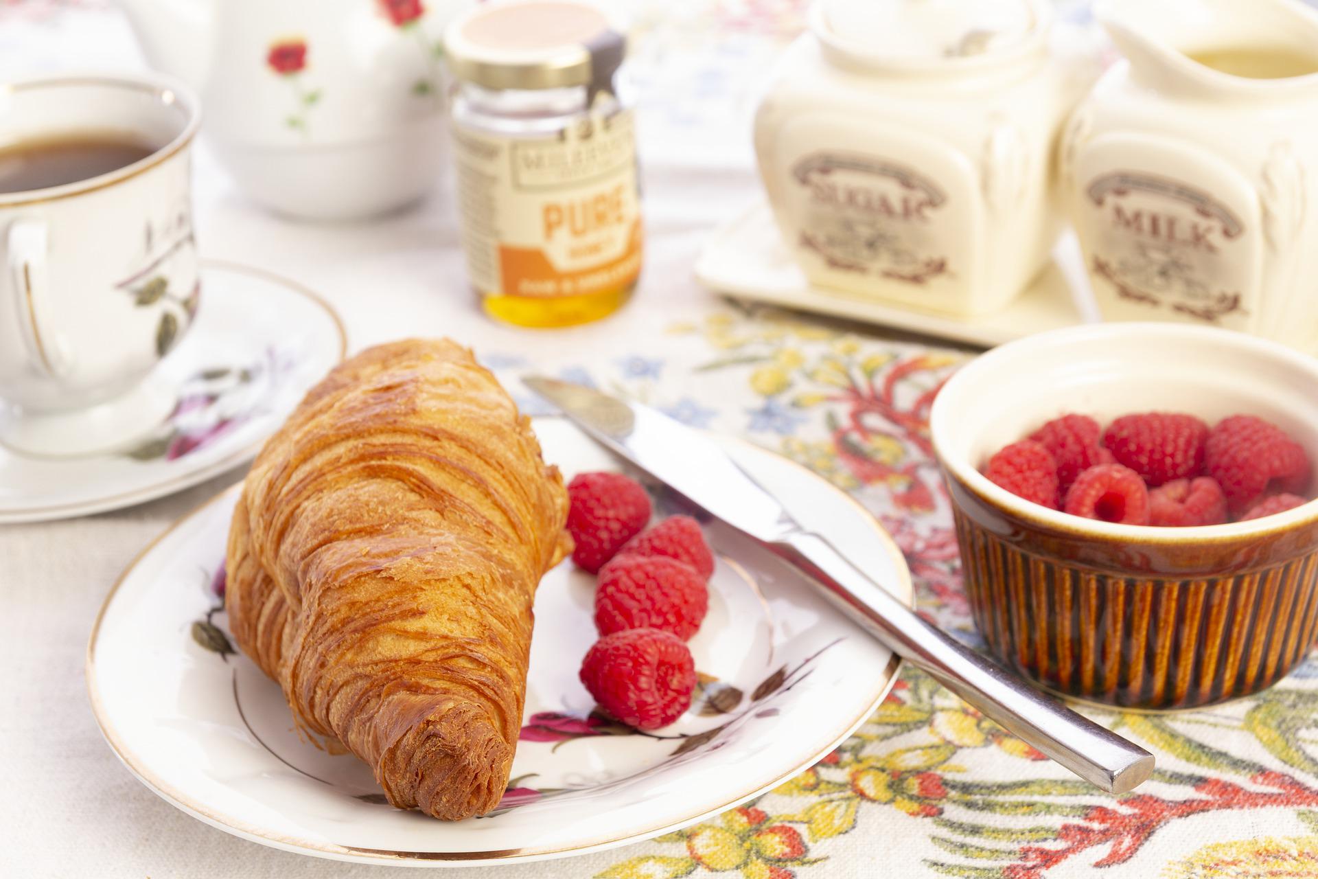 A croissant served with some raspberries
