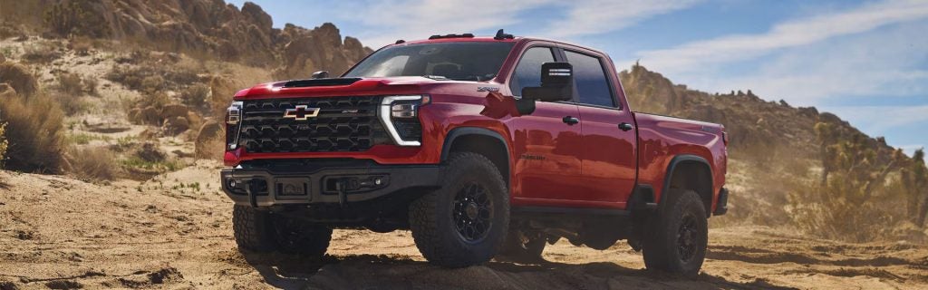 Red Chevrolet Silverado pickup truck on rugged off-road terrain.