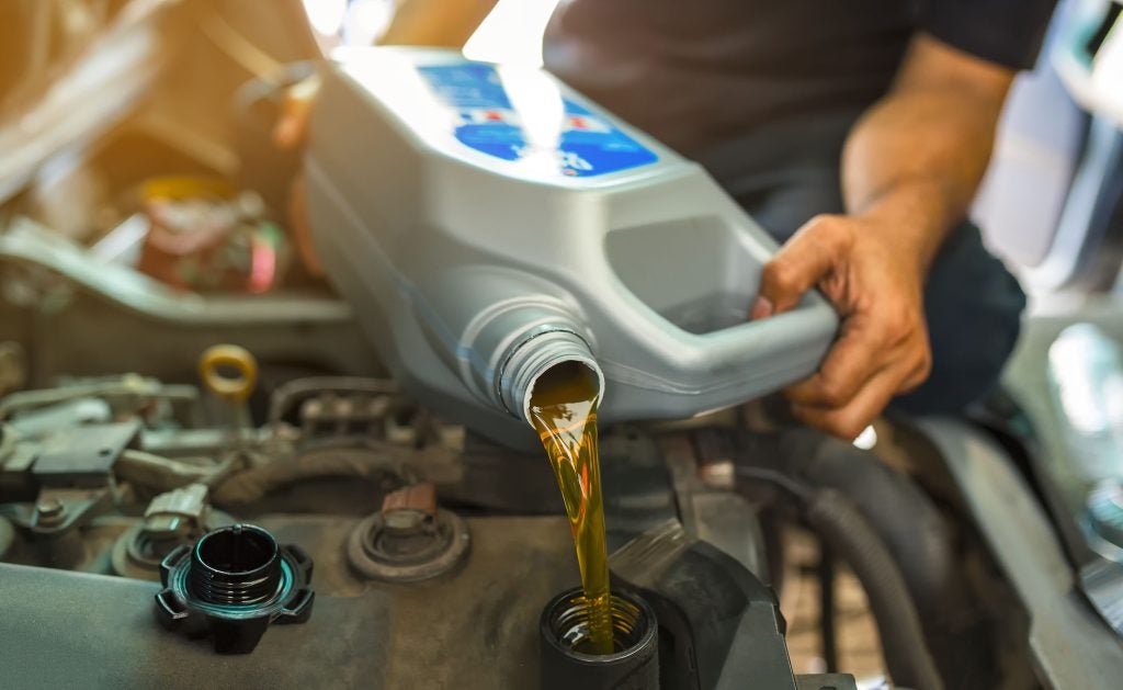 Person pouring oil into a car engine during oil change.