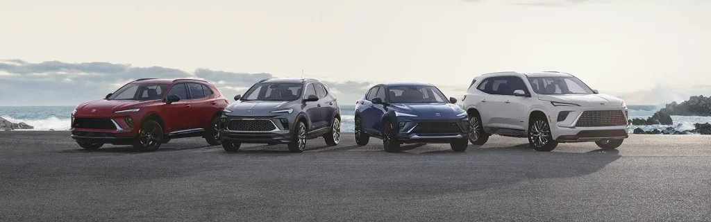 Four Buick SUVs lined up on a coastal road with the ocean in the background.