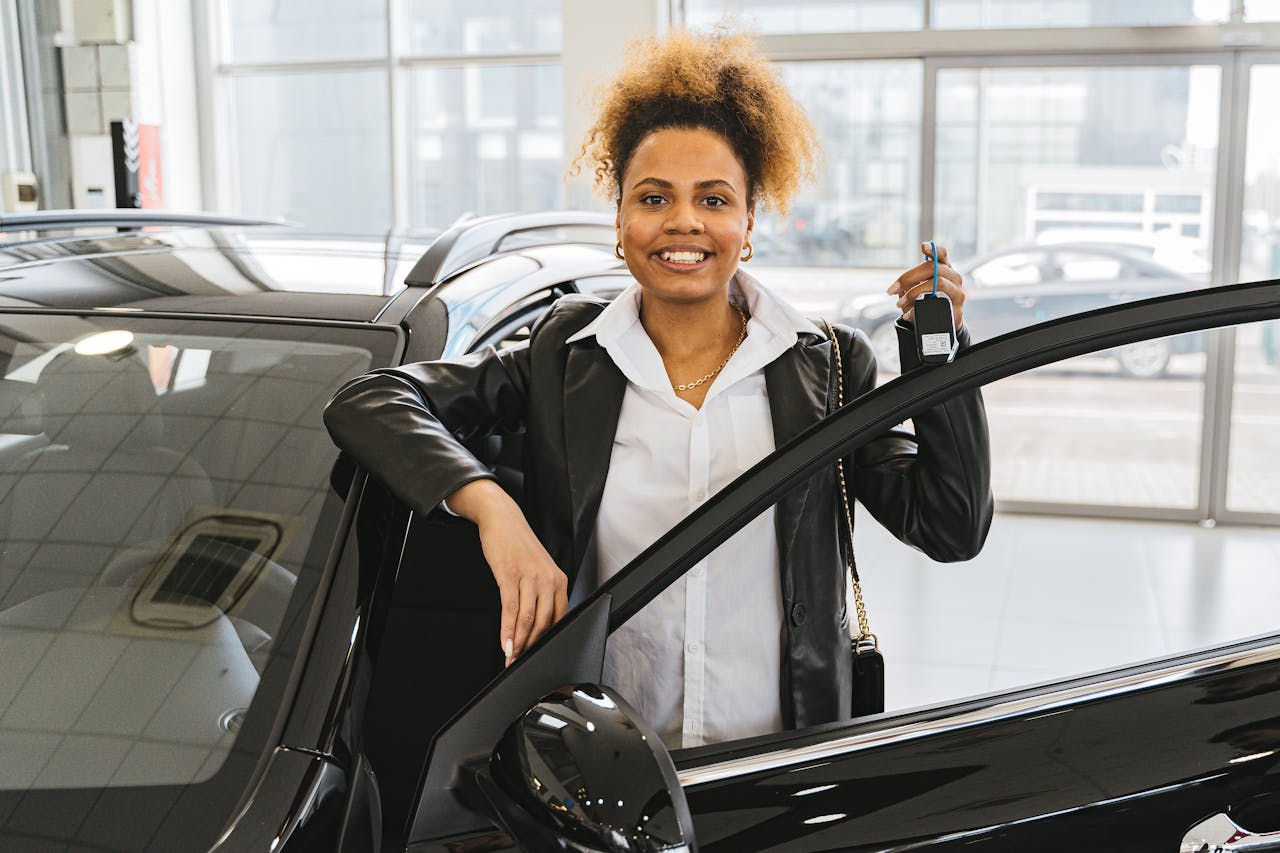 Woman in a black blazer holds car keys while smiling