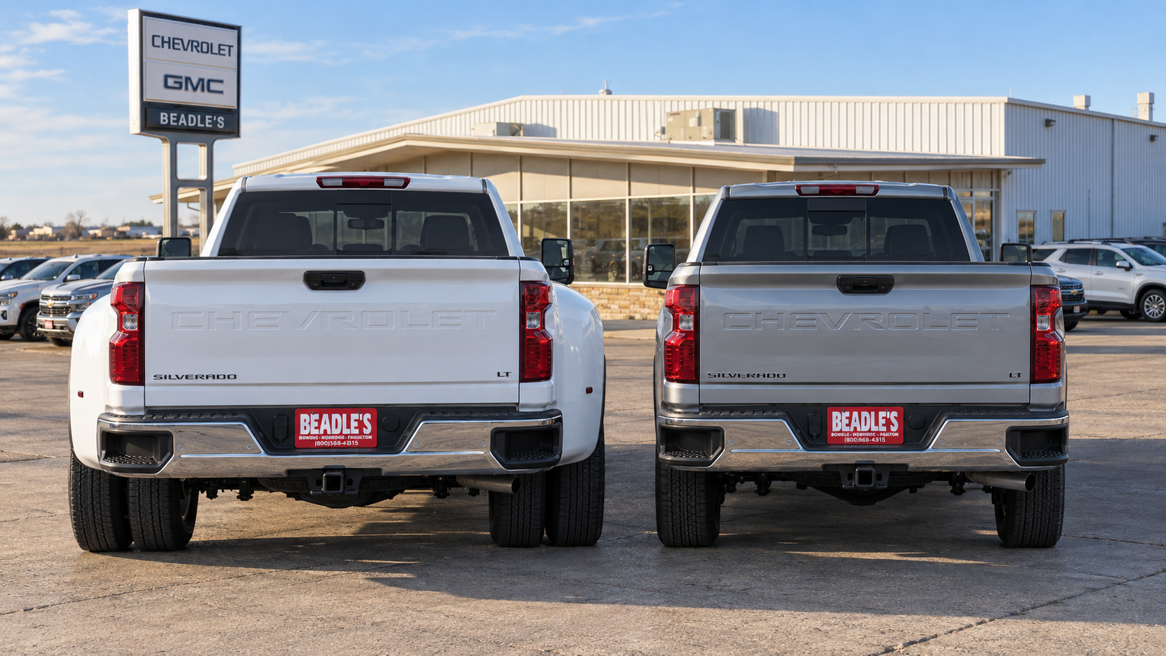 A Chevrolet Silverado 3500 HD dually parked beside a single-rear-wheel Silverado 3500 HD, tailgates to the camera, showing the width difference