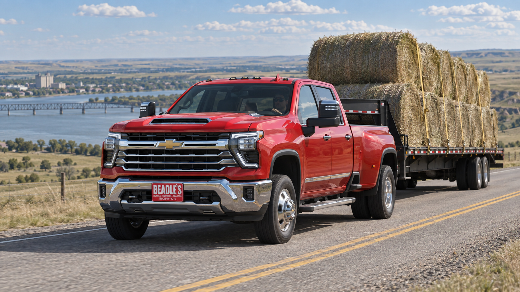 Chevrolet Silverado 3500 HD dually in Red Hot pulling a gooseneck flatbed stacked with round bales on US Highway 12 near Mobridge