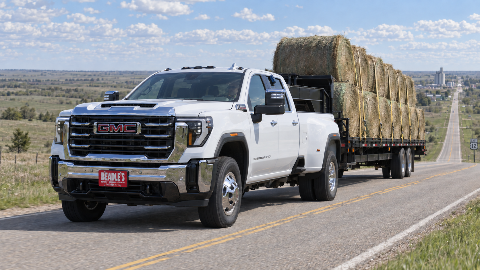 GMC Sierra 3500 HD dually pulling a gooseneck flatbed of round bales up a Highway 12 grade near Mobridge, South Dakota