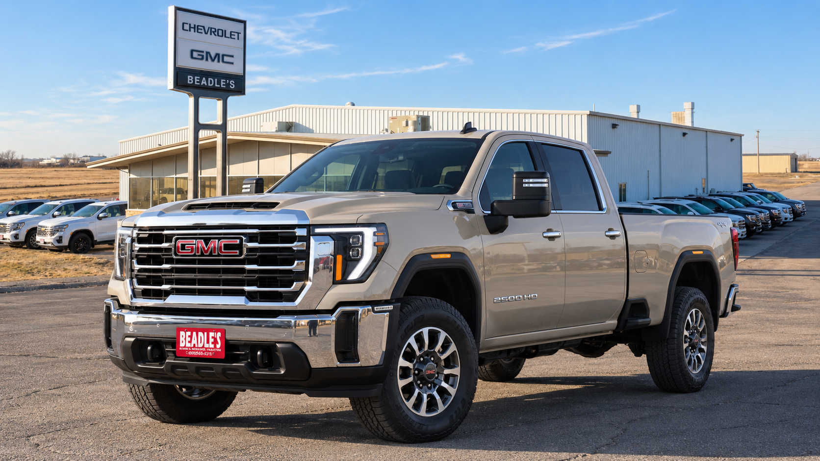 Coastal Dune 2027 GMC Sierra 2500 HD SLE on 18-inch wheels parked in front of the showroom at Beadle Chevrolet GMC in Mobridge