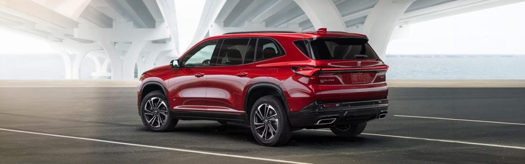 Red Buick SUV parked near a modern waterfront structure.