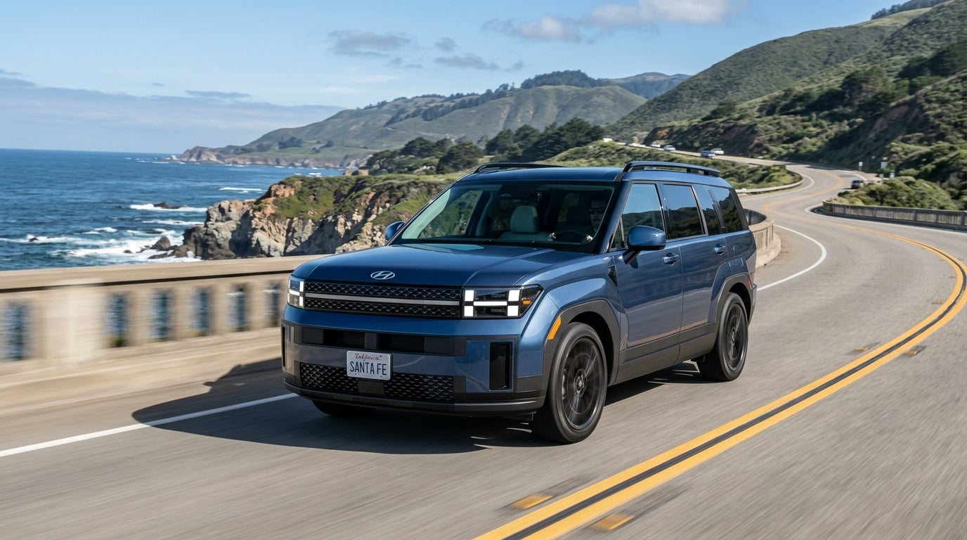 Blue Hyundai Santa Fe driving along a scenic coastal highway with ocean cliffs in the background. (Representative image for illustration purposes only. Actual vehicle may vary based on trim and configuration.)