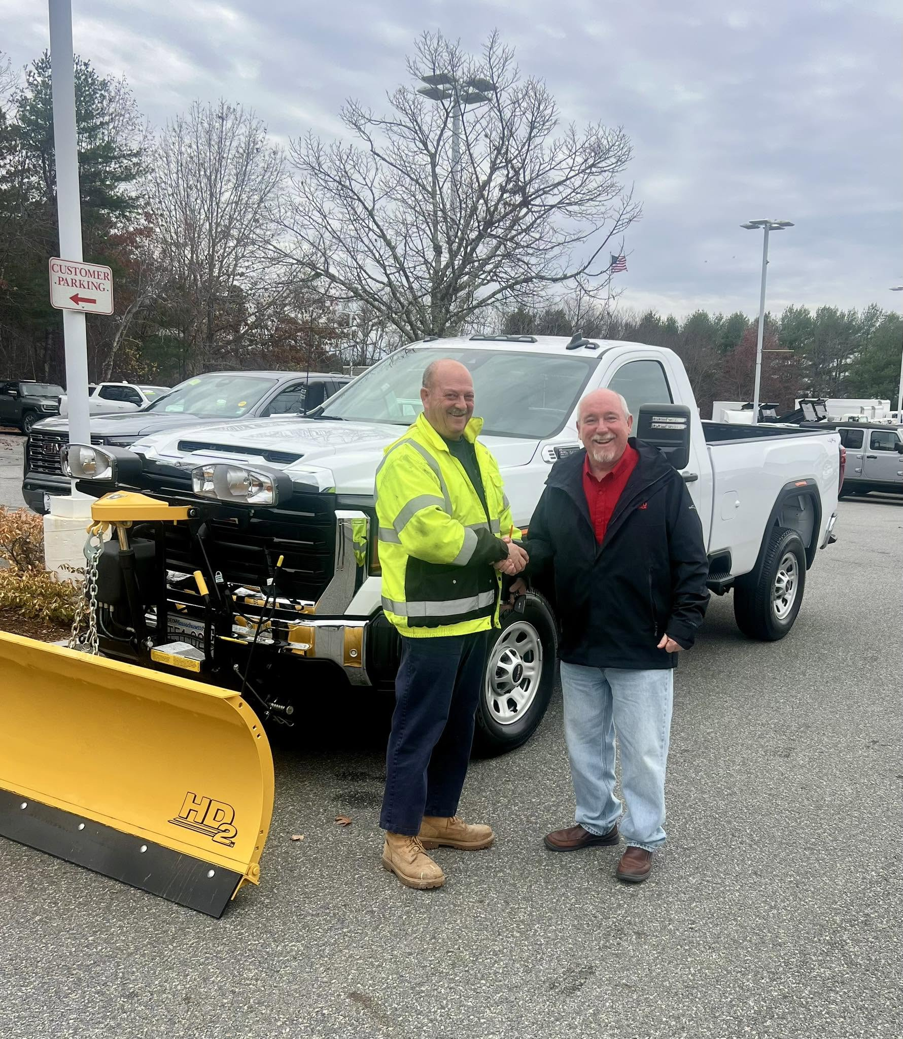 Customer delivery beside a white GMC truck equipped with a FISHER plow