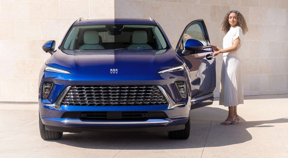 Front angle view of a woman opening the driver side door of a blue 2025 Buick Envision.