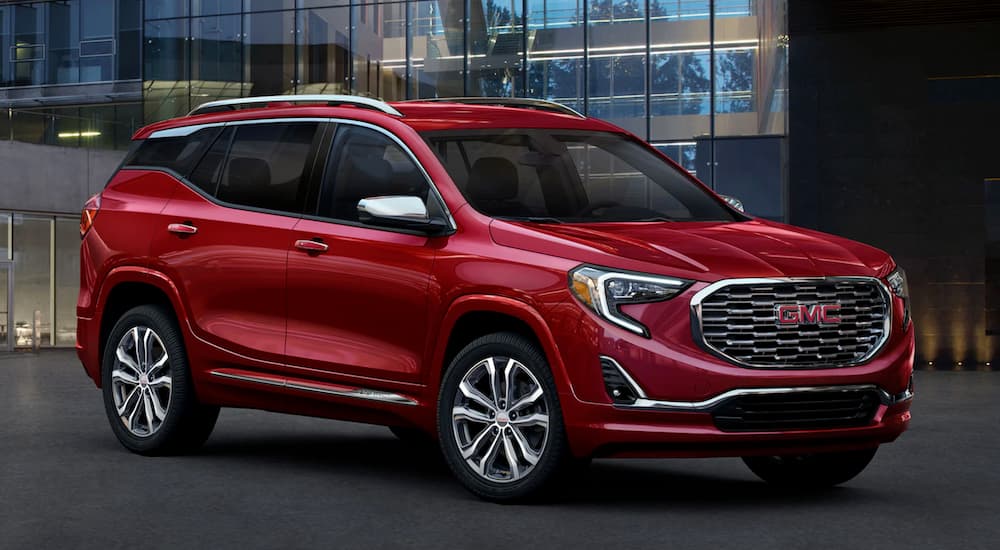 Red 2020 GMC Terrain parked outside a dealer with used cars for sale.