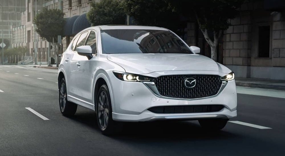 White 2021 Mazda CX-5 driving through a city.