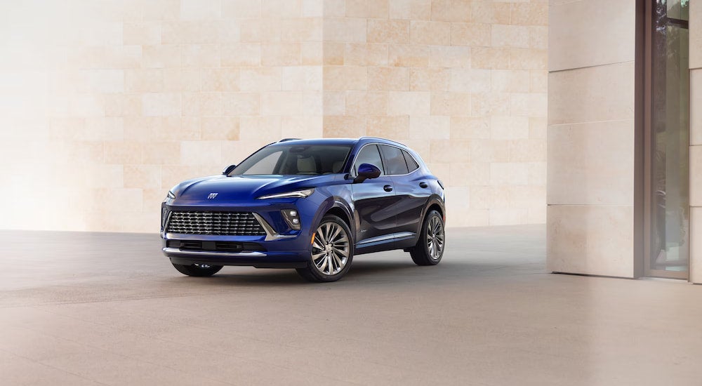 A blue 2025 Buick Envision parked in front of a wall at a Buick dealer.
