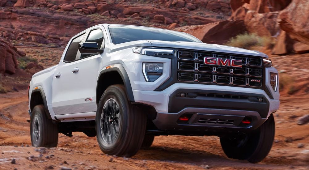 A white 2026 GMC Canyon AT4 shown driving through canyons.