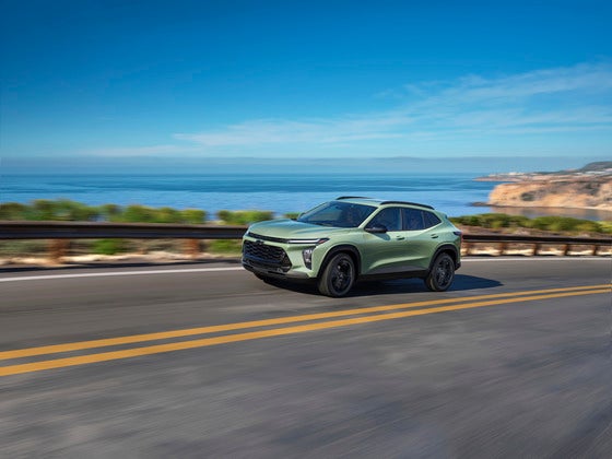 A vibrant 2025 Chevrolet Trax Activ in Cactus Green cruising along a scenic coastal highway, showcasing its adventurous spirit and stylish design