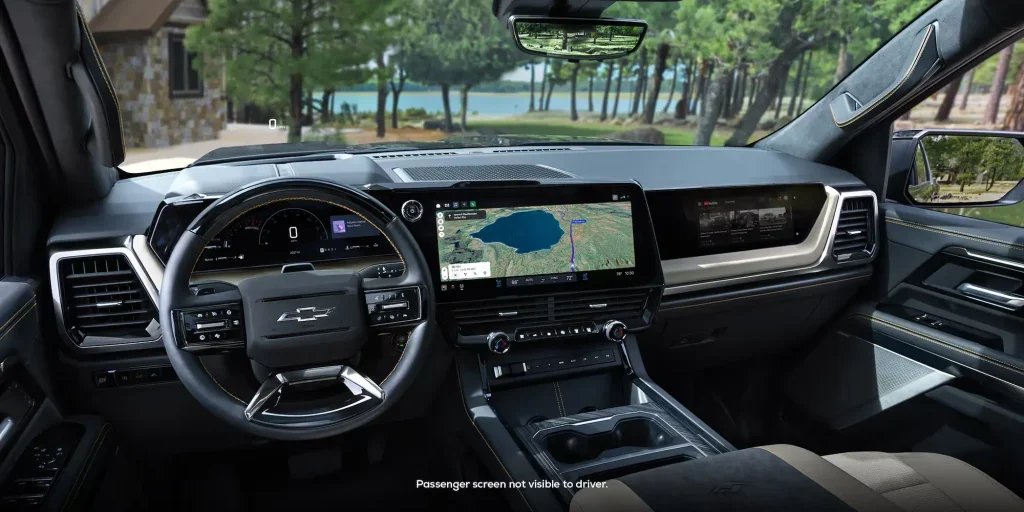 Photo of the driver cockpit in the 2027 Chevrolet Silverado including driver information display behind the steering wheel, larger infotainment system with google maps on it, and a passenger screen displaying YouTube.
